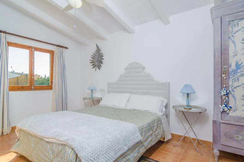 Un dormitorio con una cama, mesas de noche y una ventana.