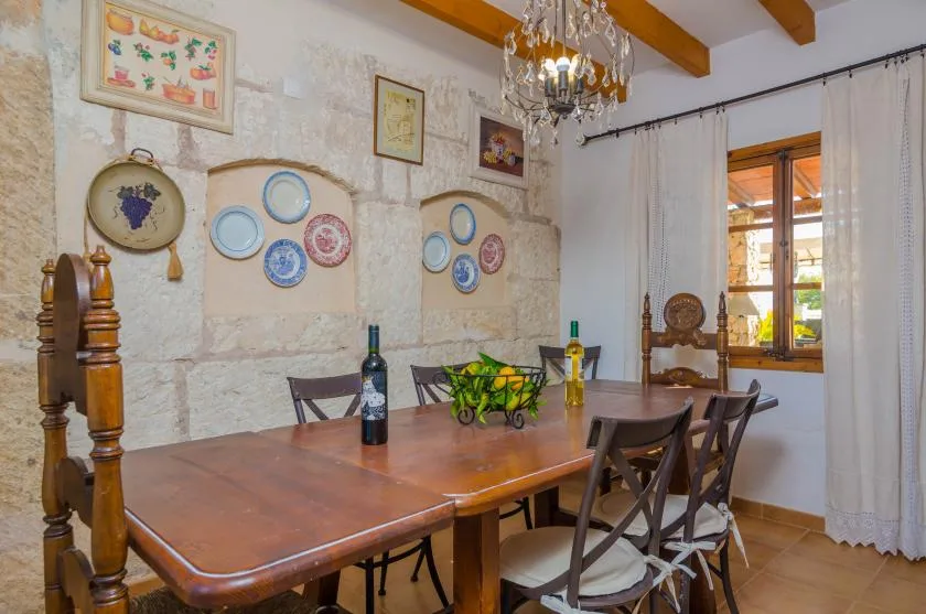 Un comedor con una mesa de madera, sillas y platos decorativos en la pared.