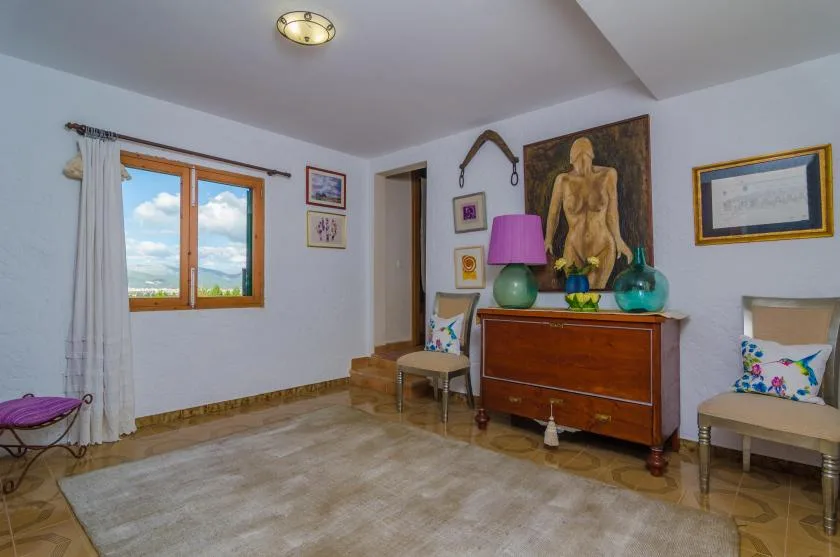 Una habitación amueblada con un mueble de madera, arte colorido y una ventana.