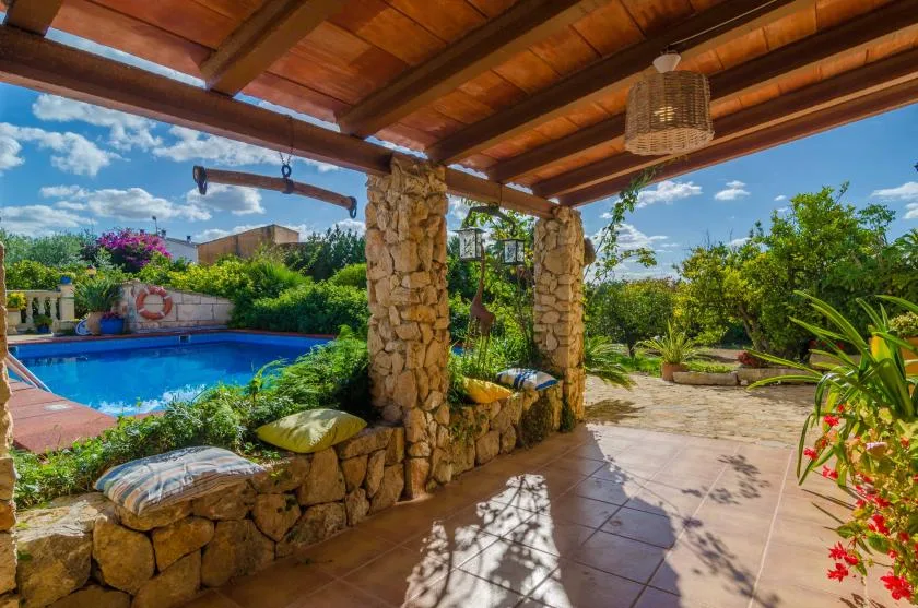 Un patio cubierto de piedra da a una piscina y al jardín.
