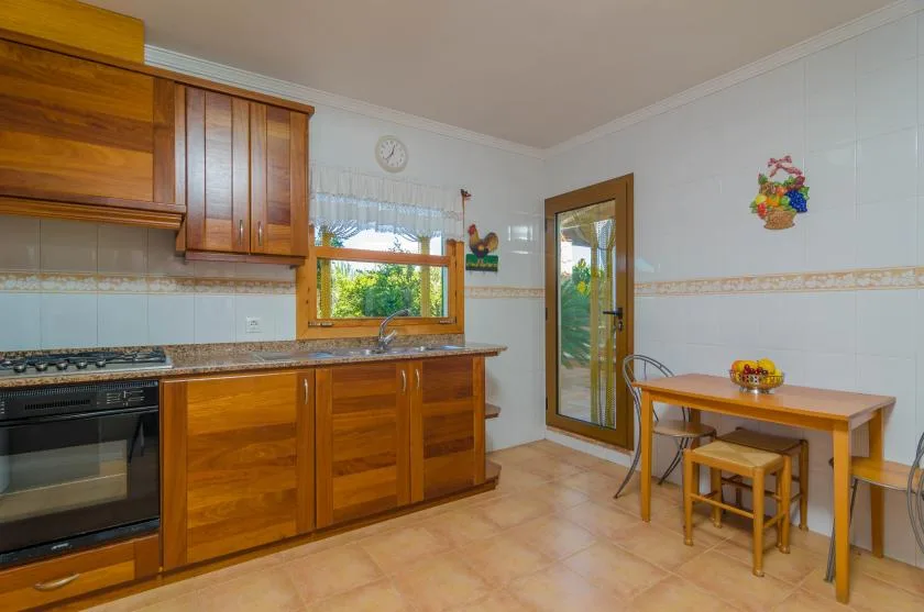 Una cocina con gabinetes de madera, una estufa y una pequeña mesa de comedor.