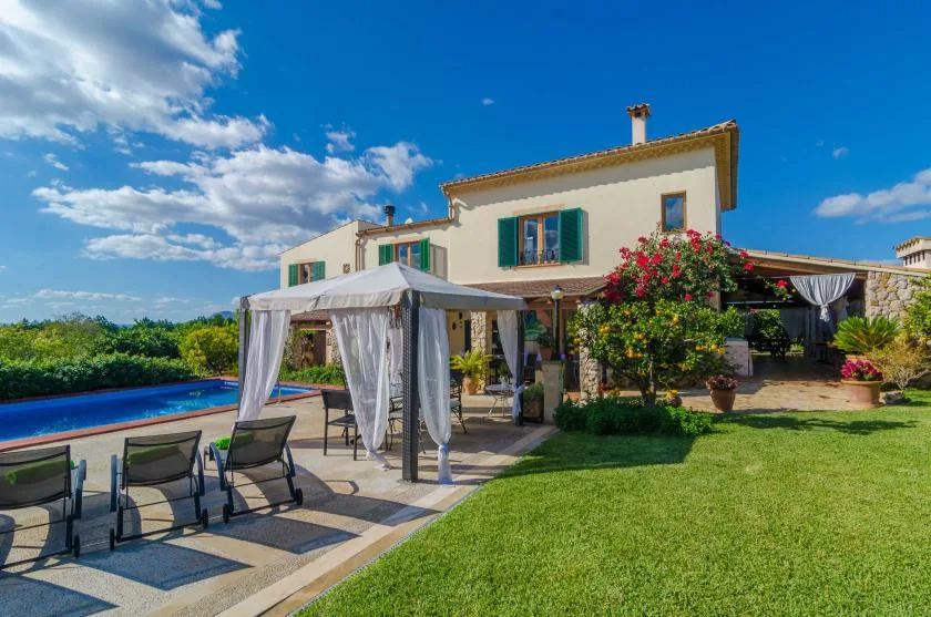Una casa con patio ajardinado, asientos al aire libre y piscina.
