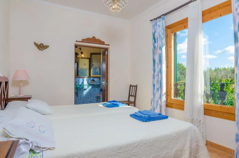 Un dormitorio luminoso con una cama bien hecha junto a grandes ventanas.