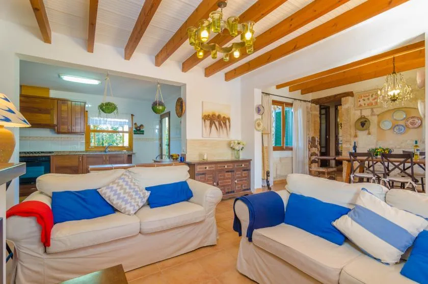 Una sala luminosa con asientos, vigas de madera en el techo y un comedor contiguo.