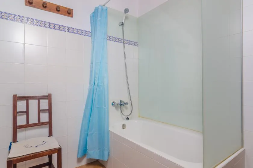 Un baño con bañera, ducha y cortina azul.