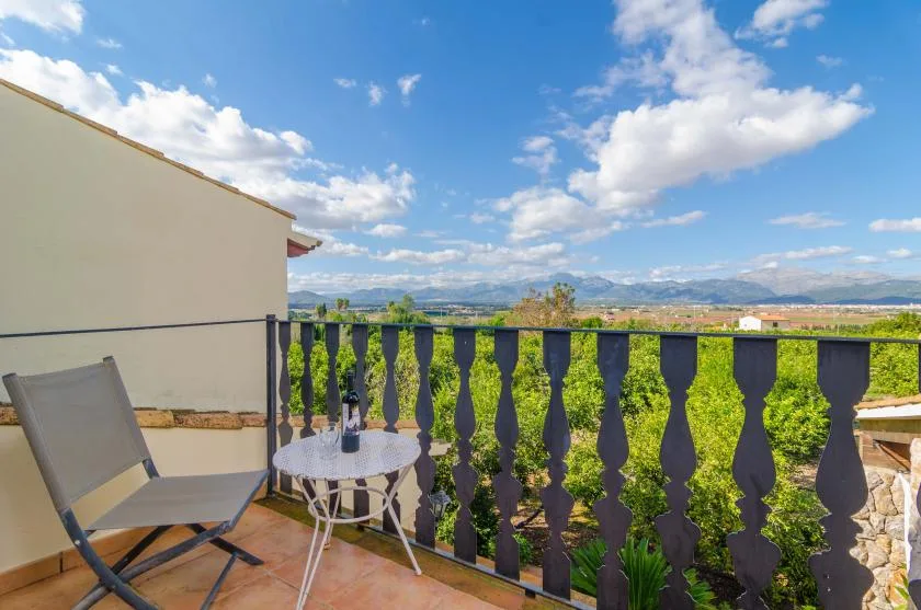 Una terraza contempla campos verdes y colinas lejanas bajo un cielo parcialmente nublado.