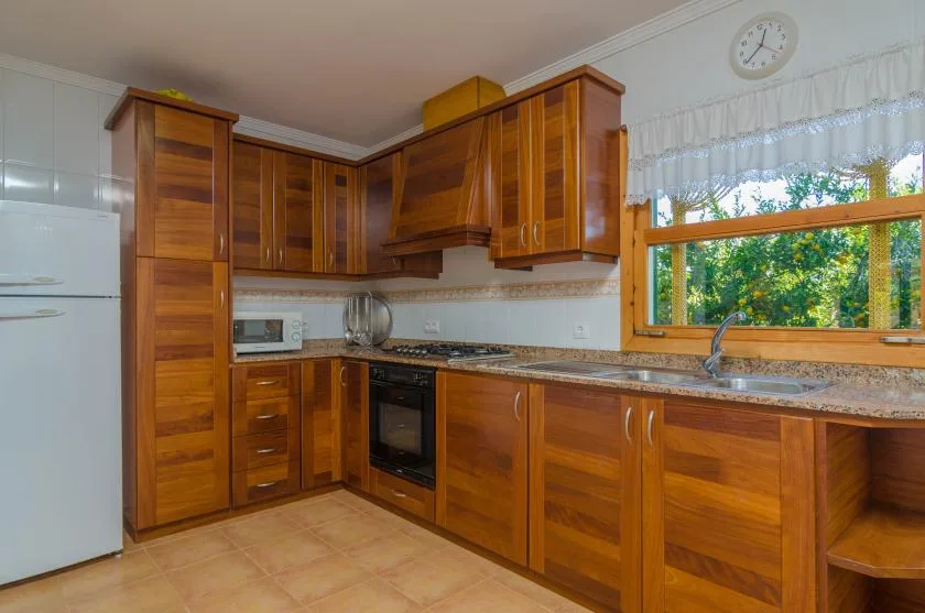 Una cocina con gabinetes de madera, una estufa y una ventana sobre el fregadero.