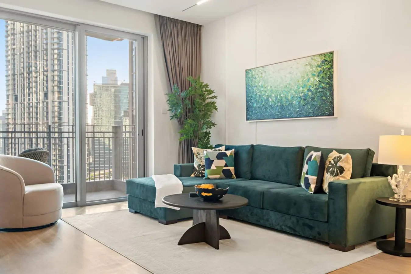 Una sala luminosa con asientos, una mesa de centro y grandes ventanas con vistas a edificios de la ciudad.