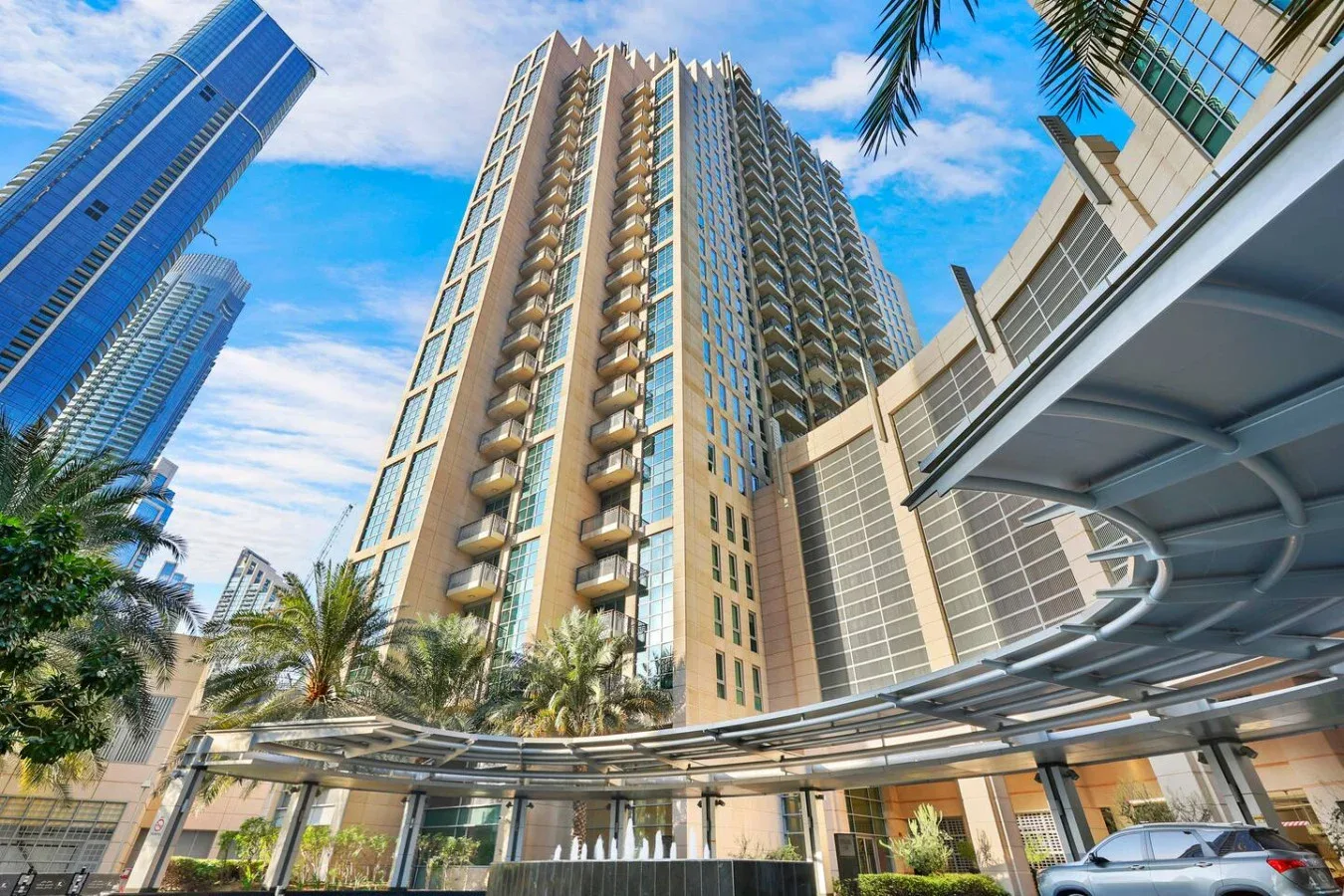 Una torre residencial alta se eleva sobre un patio de entrada ajardinado.