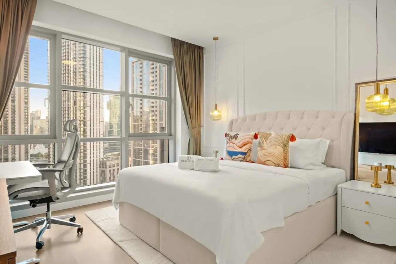 A bright bedroom with a large bed beside floor-to-ceiling windows.