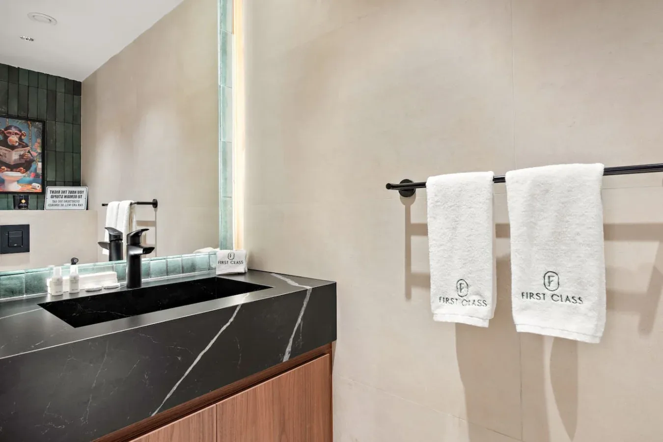 Lavabo de baño con un fregadero negro y toallas blancas colgadas en la pared.