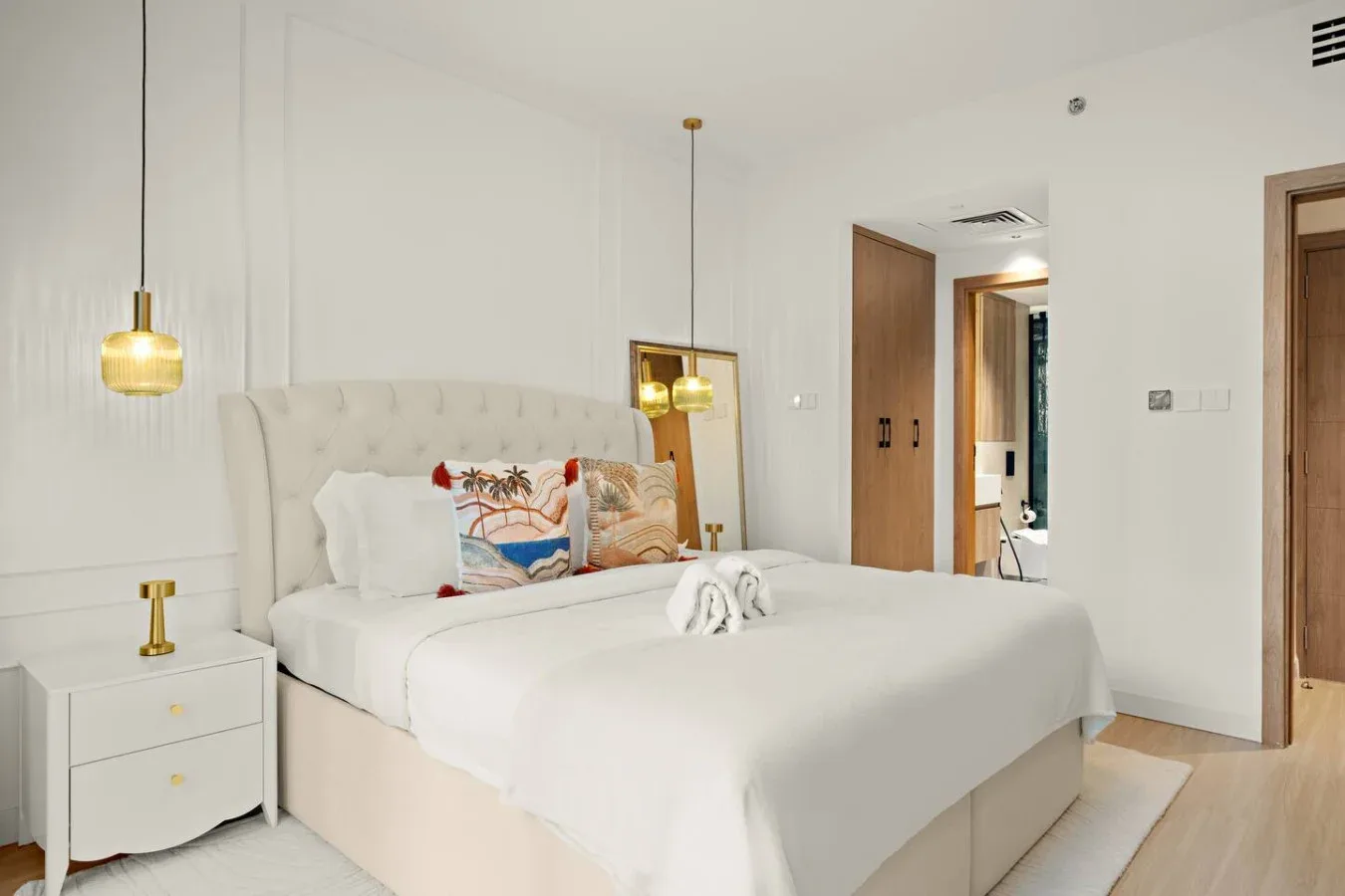 Un dormitorio luminoso con una cama bien tendida y mesitas de noche.