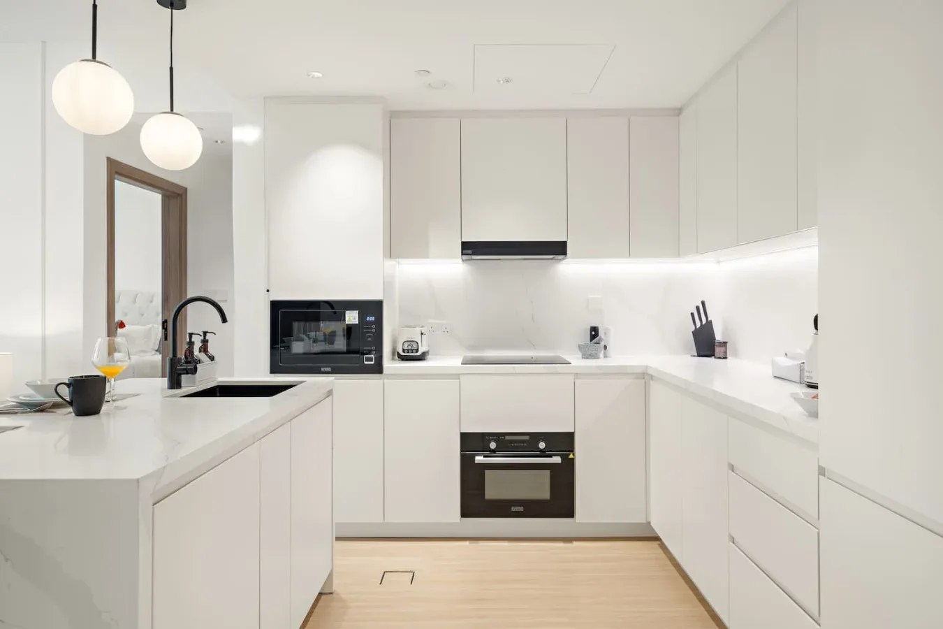 Una cocina moderna y luminosa con gabinetes blancos y un horno central.