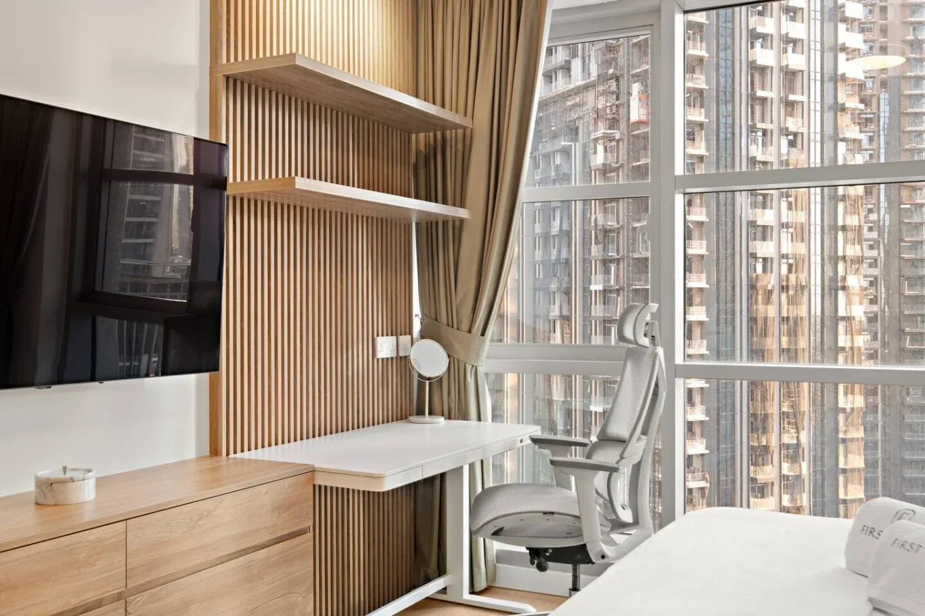 Una habitación luminosa con escritorio y asientos junto a grandes ventanas.