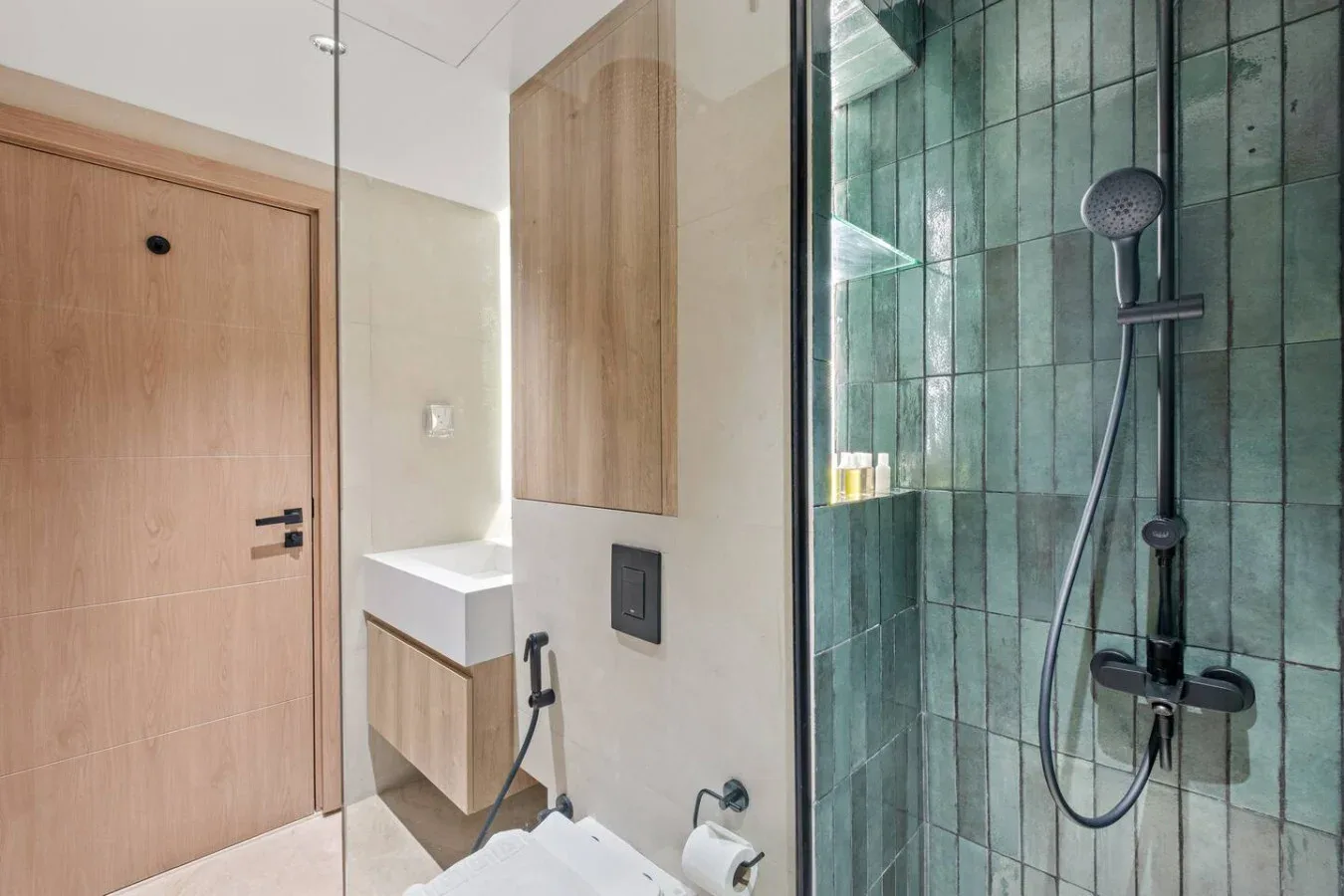 Un baño con ducha de vidrio y lavabo montado en la pared.