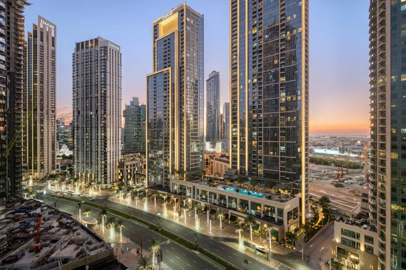Un horizonte urbano al atardecer, con edificios altos iluminados y calles abajo.