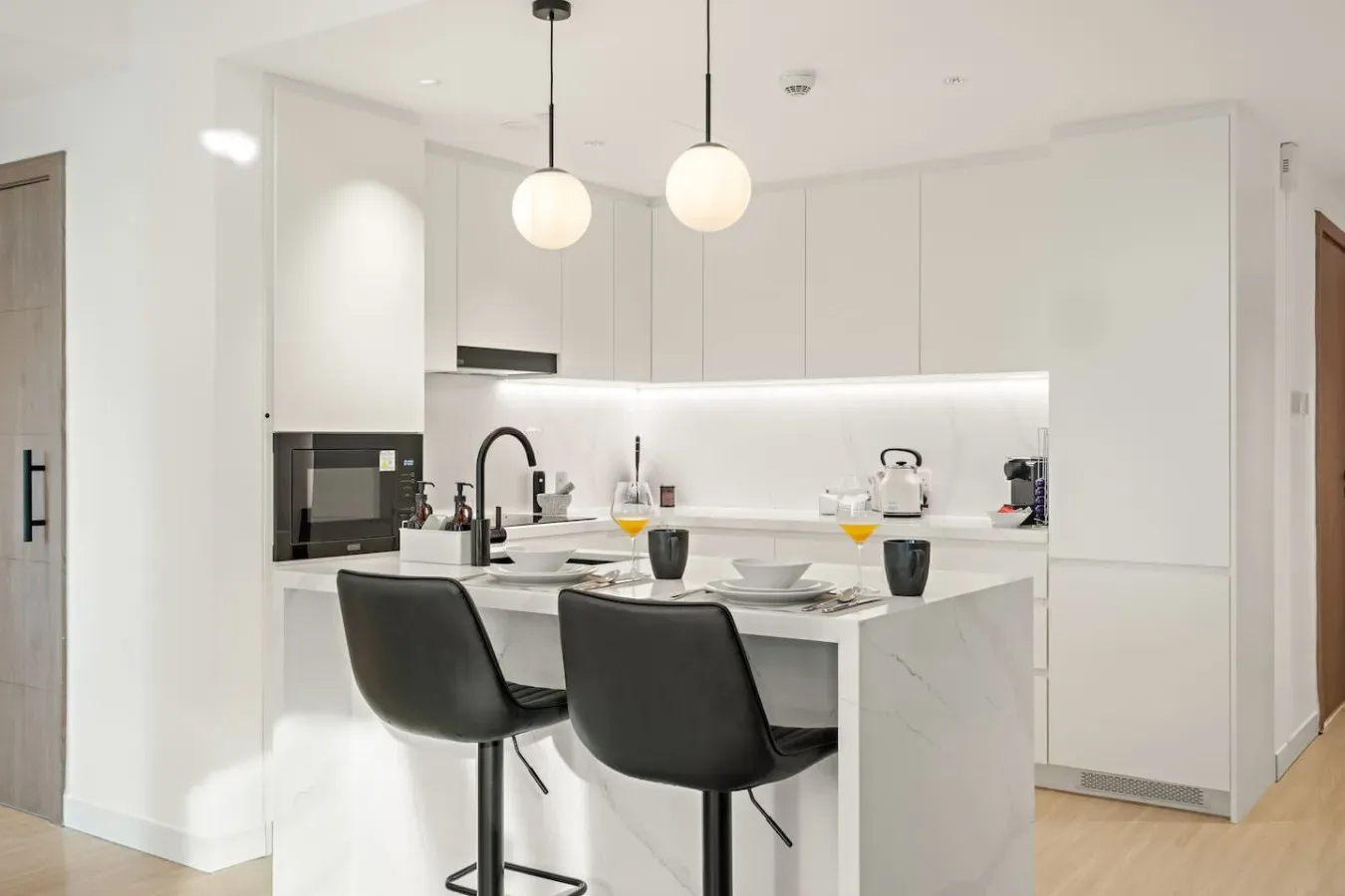 A bright modern kitchen with a central island and two pendant lights.