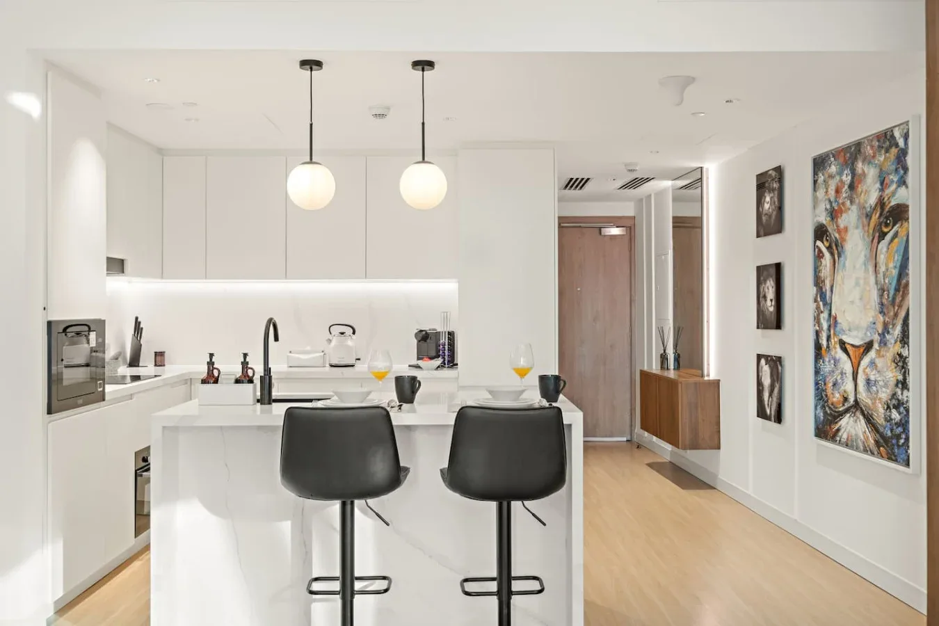 Una cocina moderna y luminosa con una isla blanca y dos taburetes oscuros.