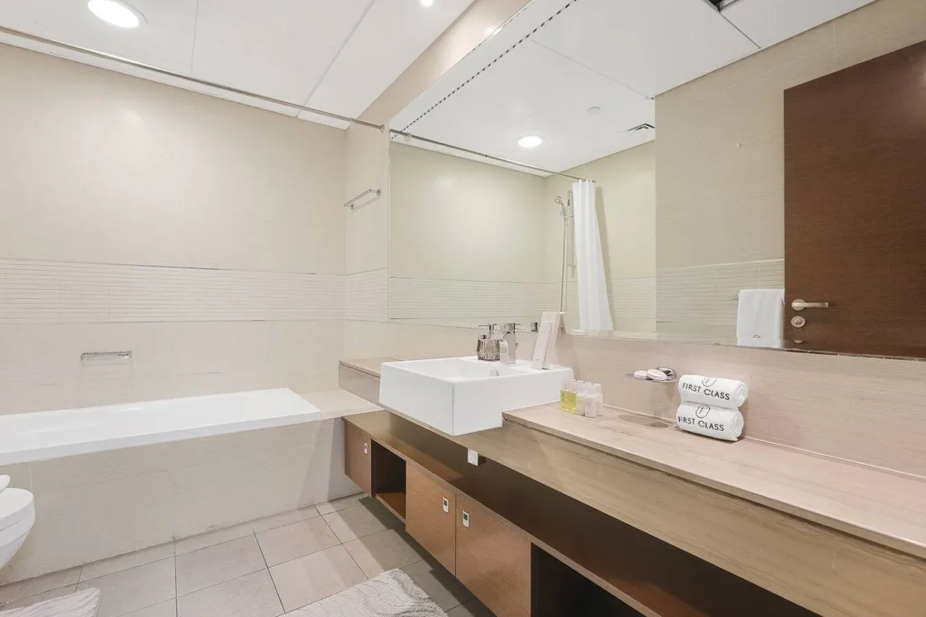 Un baño luminoso con un largo tocador y un gran espejo de pared.