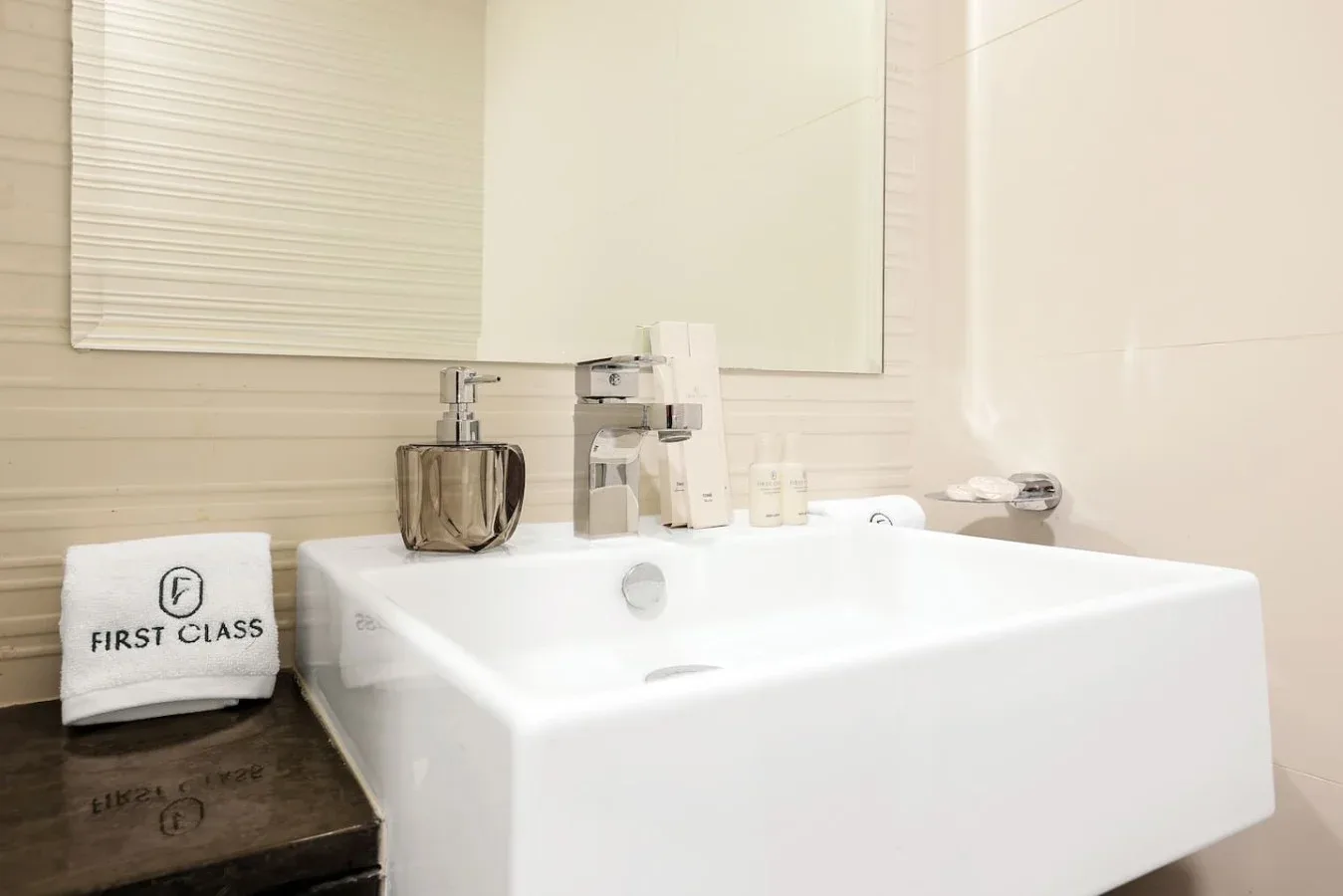 Un tocador de baño con un lavabo blanco amplio y artículos de aseo sobre la encimera.