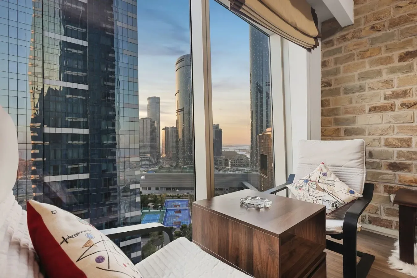Una zona de estar junto a la ventana ofrece vistas del horizonte urbano.