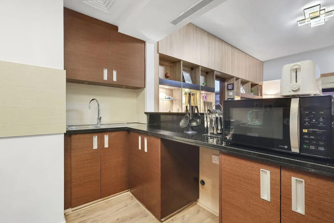 Una cocina con gabinetes de madera, un fregadero y electrodomésticos sobre la encimera.