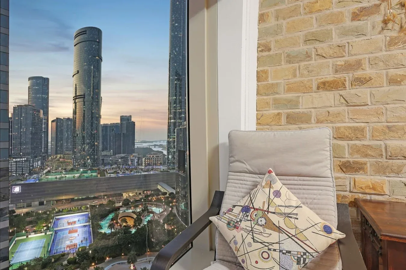 Una zona de estar en altura ofrece vistas del horizonte urbano a través de una gran ventana.