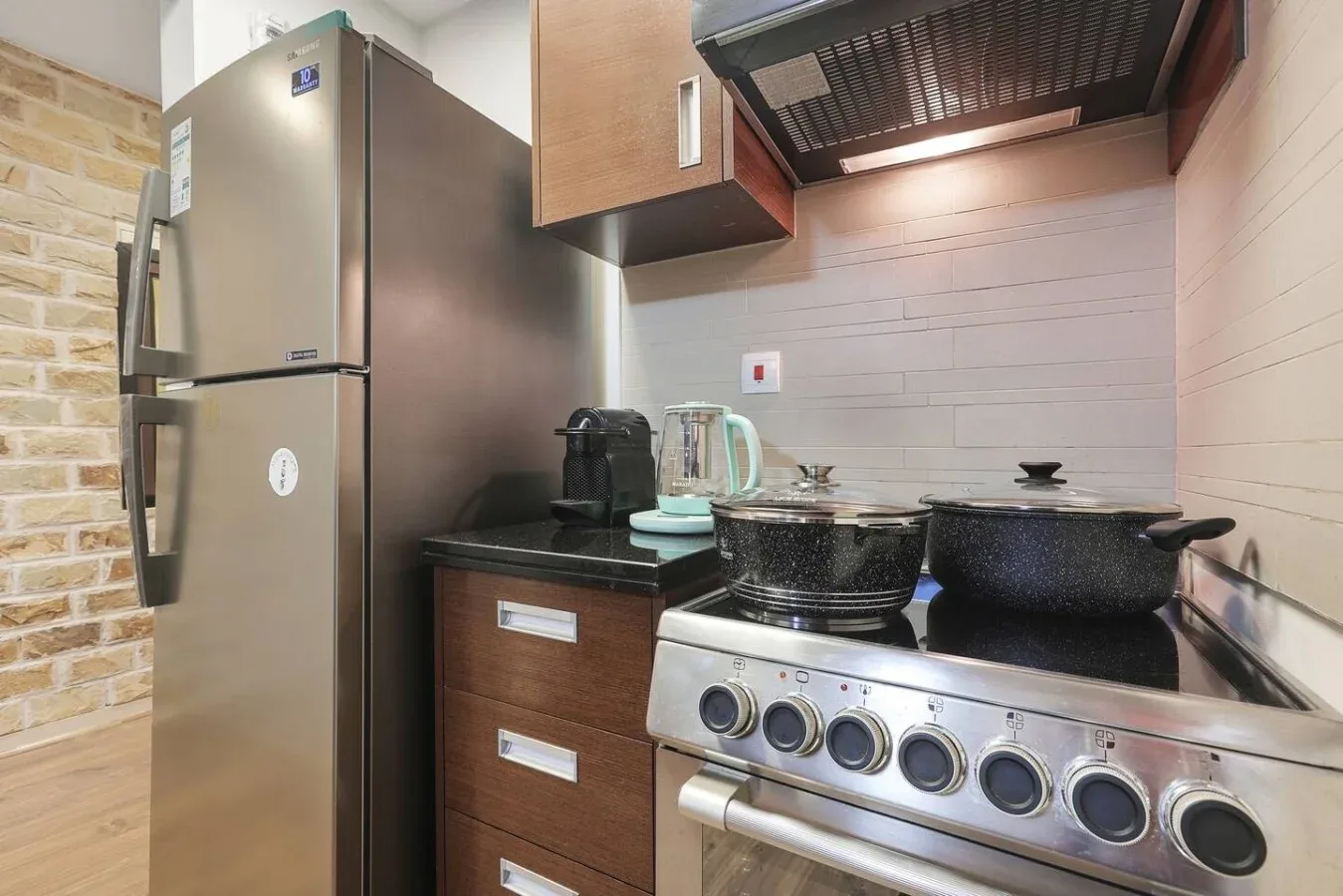 Una cocina compacta con un refrigerador de acero inoxidable y ollas sobre la estufa.