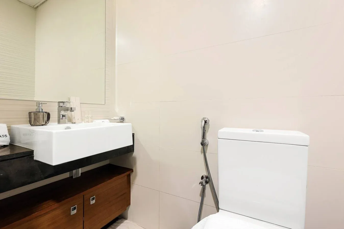 Un baño con lavabo, inodoro y ducha de mano.