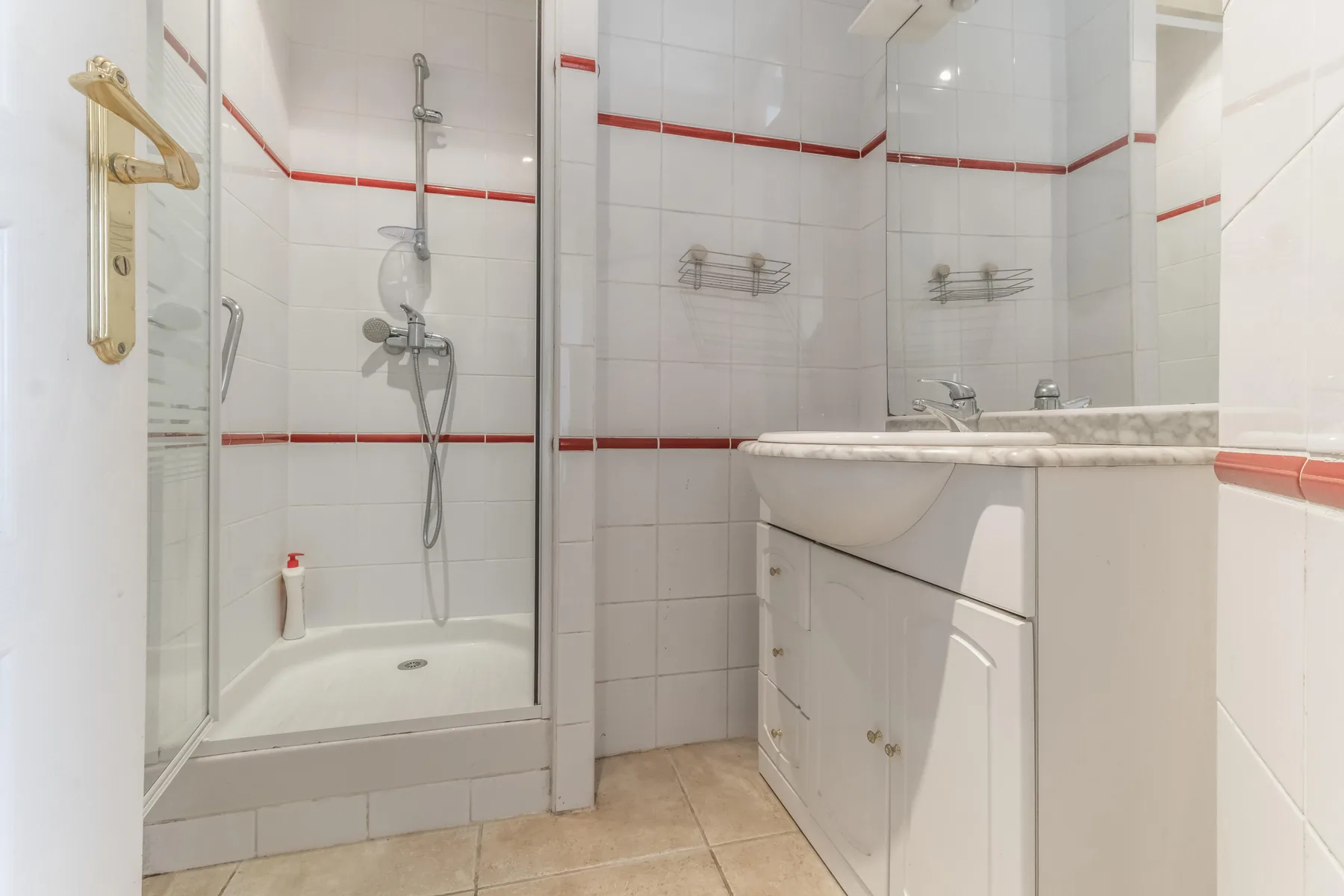 A tiled bathroom with a shower and sink vanity.