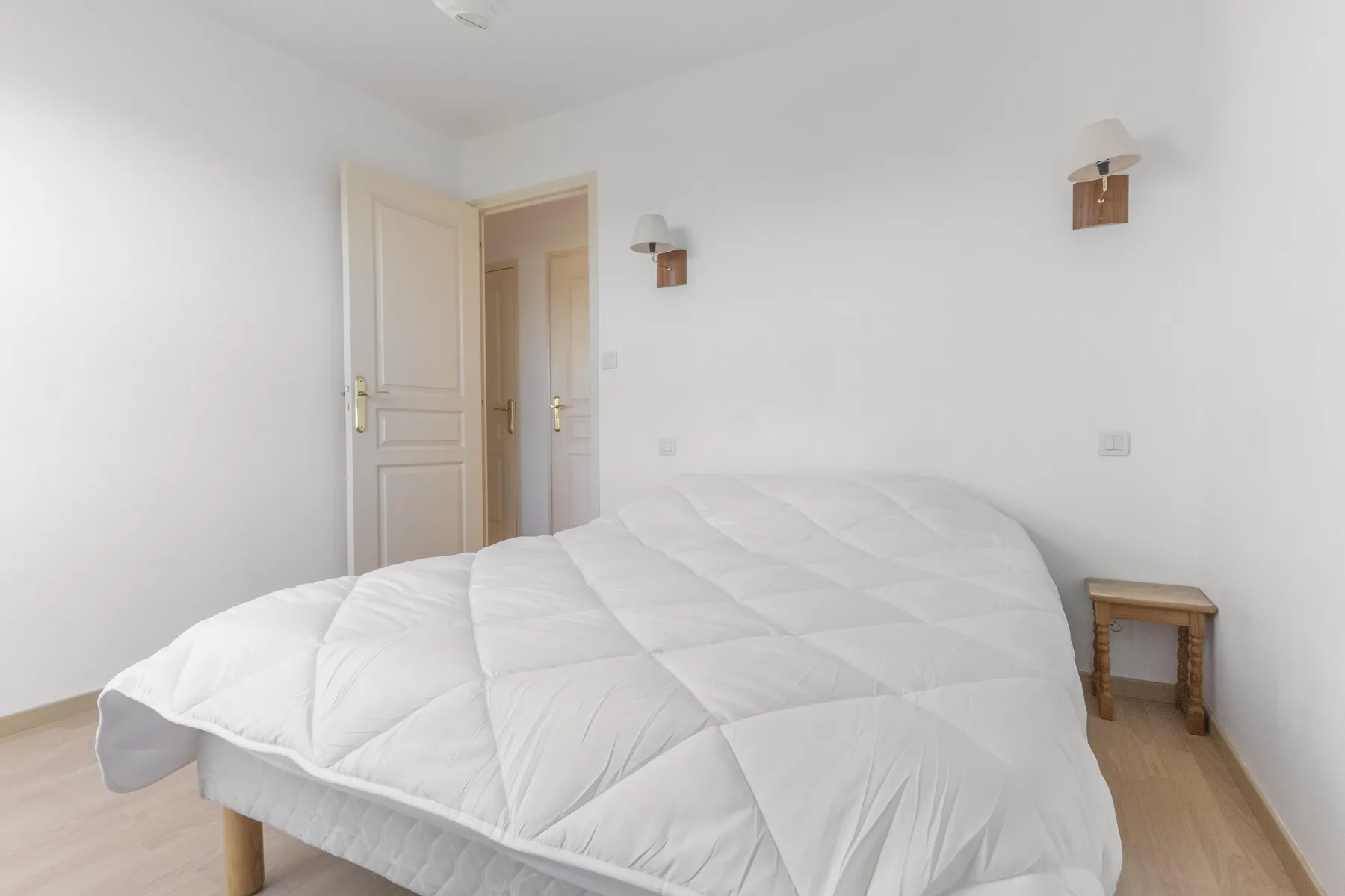 A bright bedroom with a bed and an open doorway.