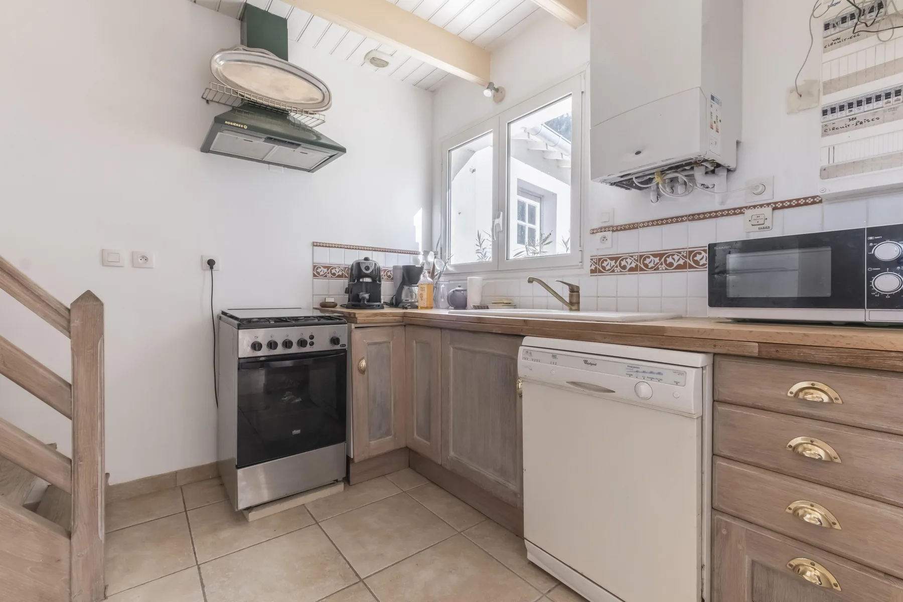 A bright kitchen with an oven, dishwasher, and countertop appliances.