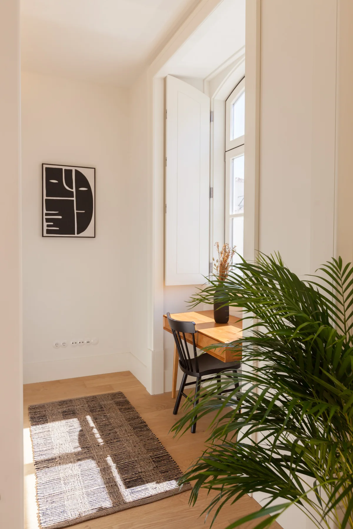 Un luminoso rincón de comedor con una mesa de madera, sillas y una planta frondosa.