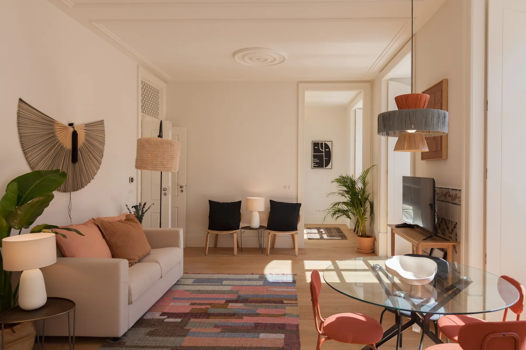 Una sala luminosa con asientos, una mesa de comedor de vidrio y plantas.