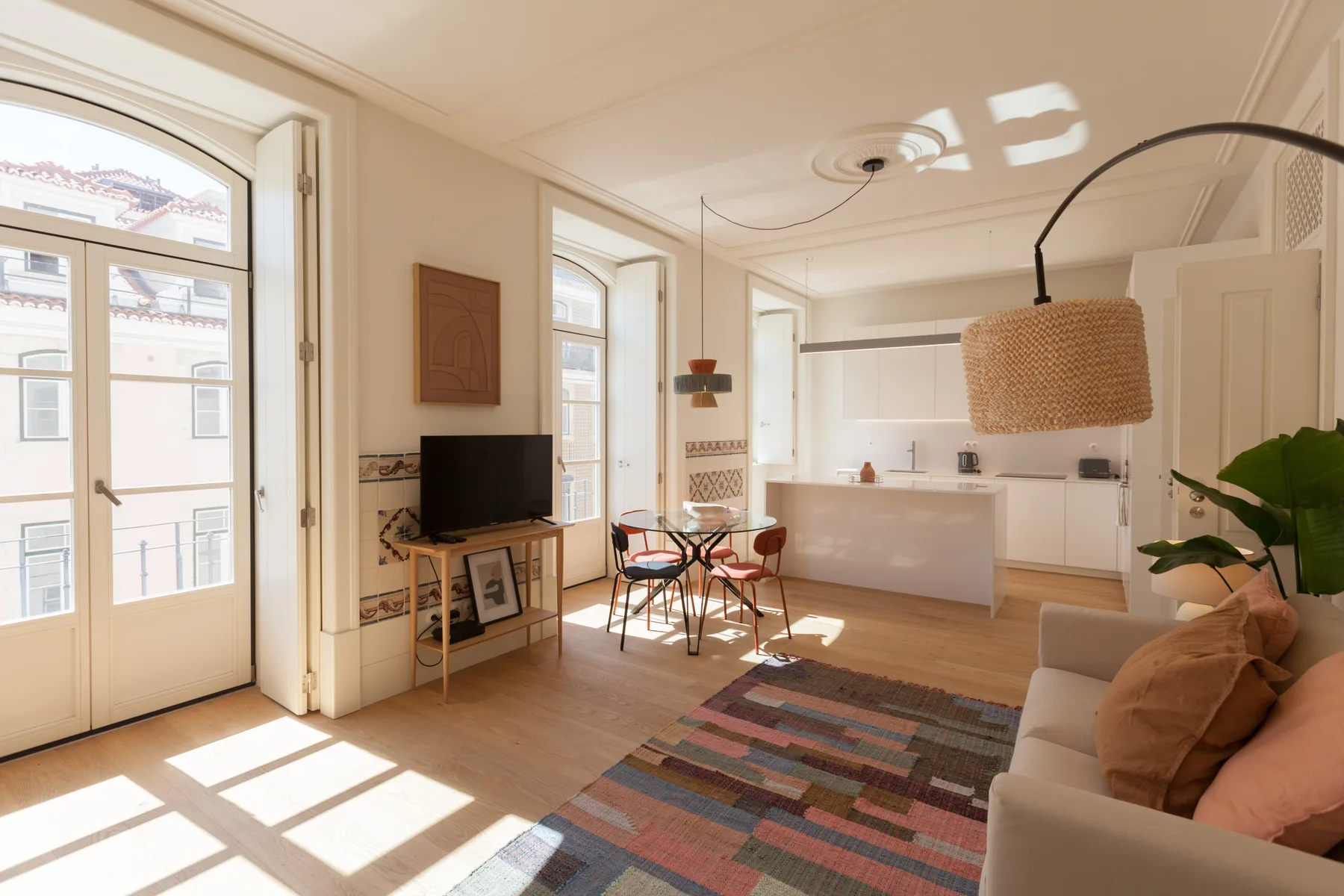 Una sala luminosa se abre a la cocina, con asientos y una mesa de comedor.