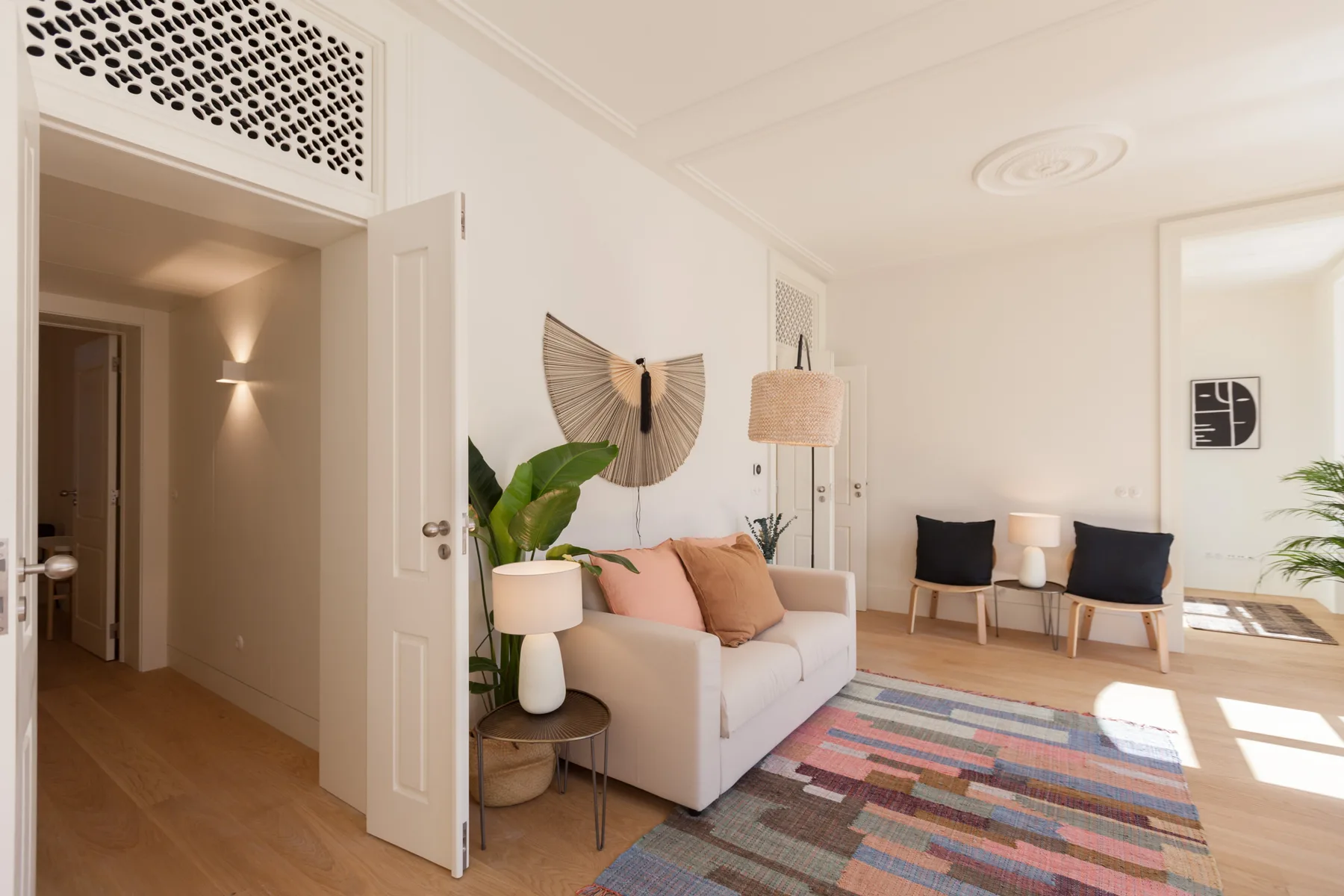 Una sala luminosa con un sofá, sillones y una alfombra colorida.