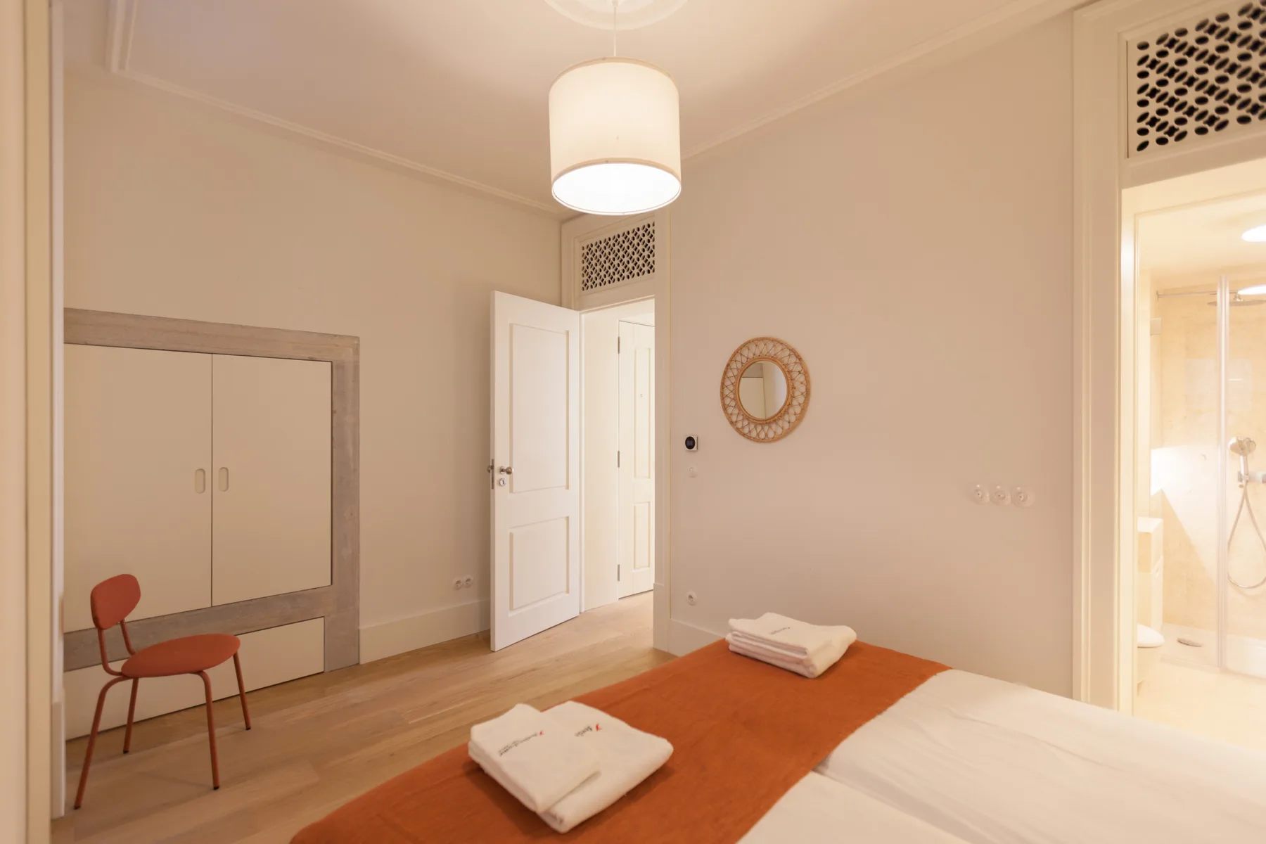 Un dormitorio luminoso con una cama, toallas dobladas y una silla.