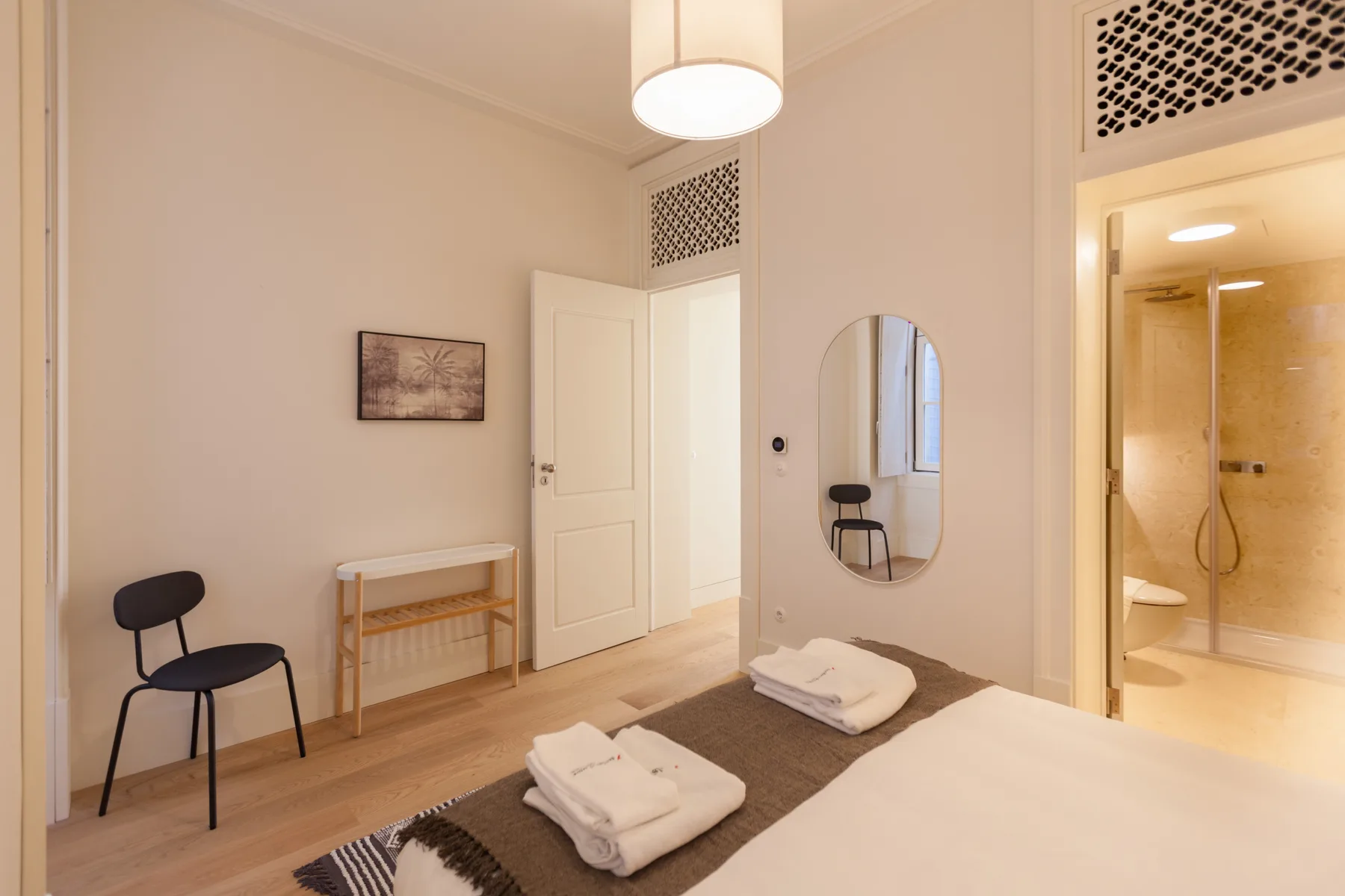 Un dormitorio con una cama, toallas dobladas y una puerta abierta al baño.