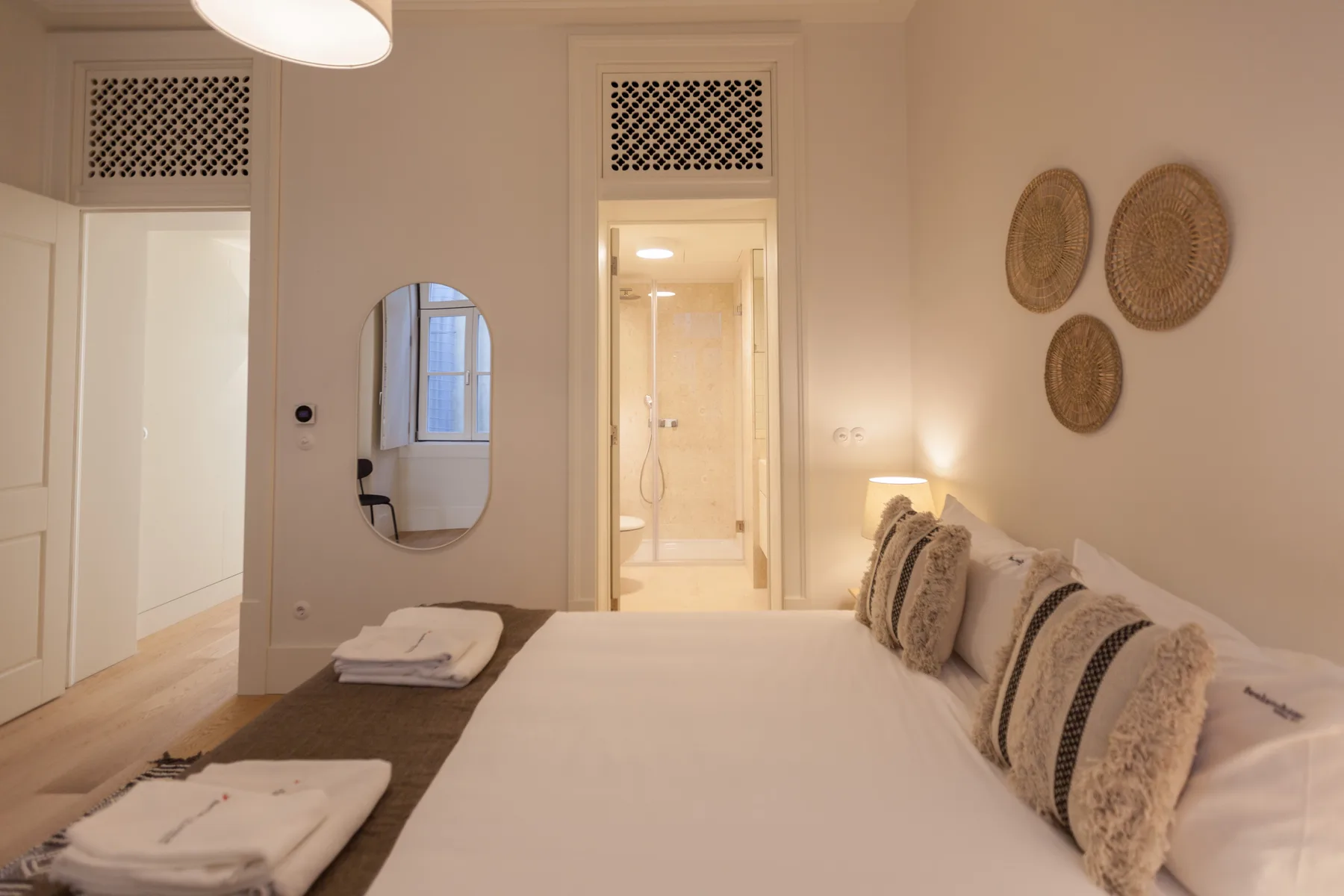 Un dormitorio con una cama bien hecha y una puerta que da a una ducha.