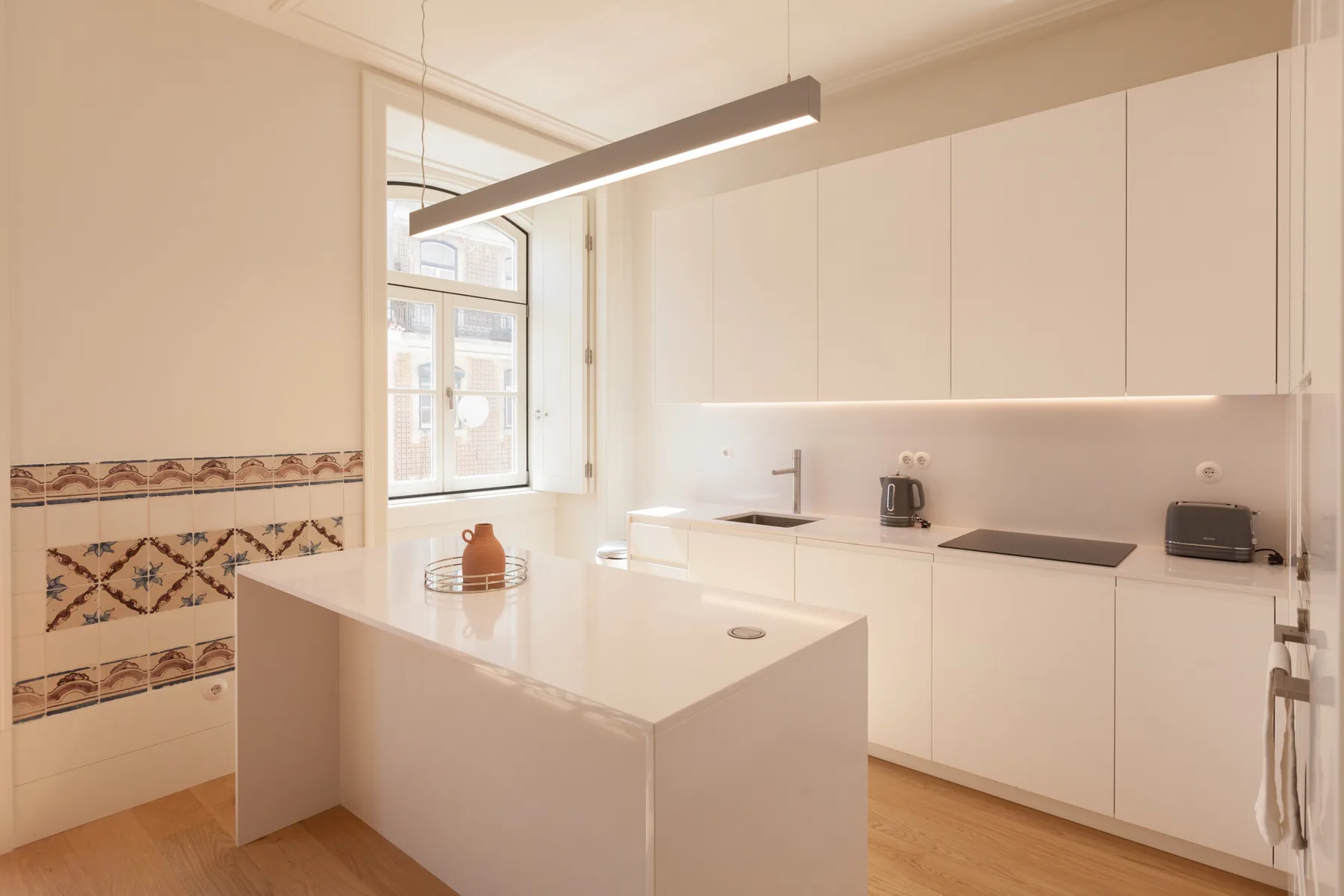 Una cocina moderna y luminosa con armarios blancos e isla central.