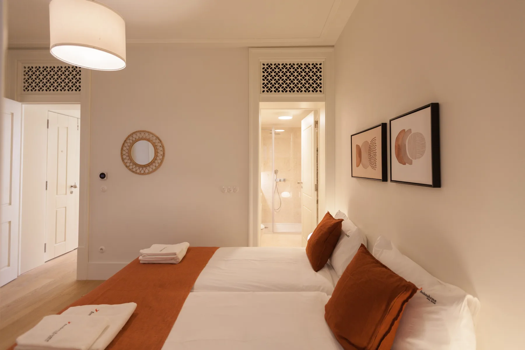 Un dormitorio con una cama bien tendida y cojines en tonos cálidos.