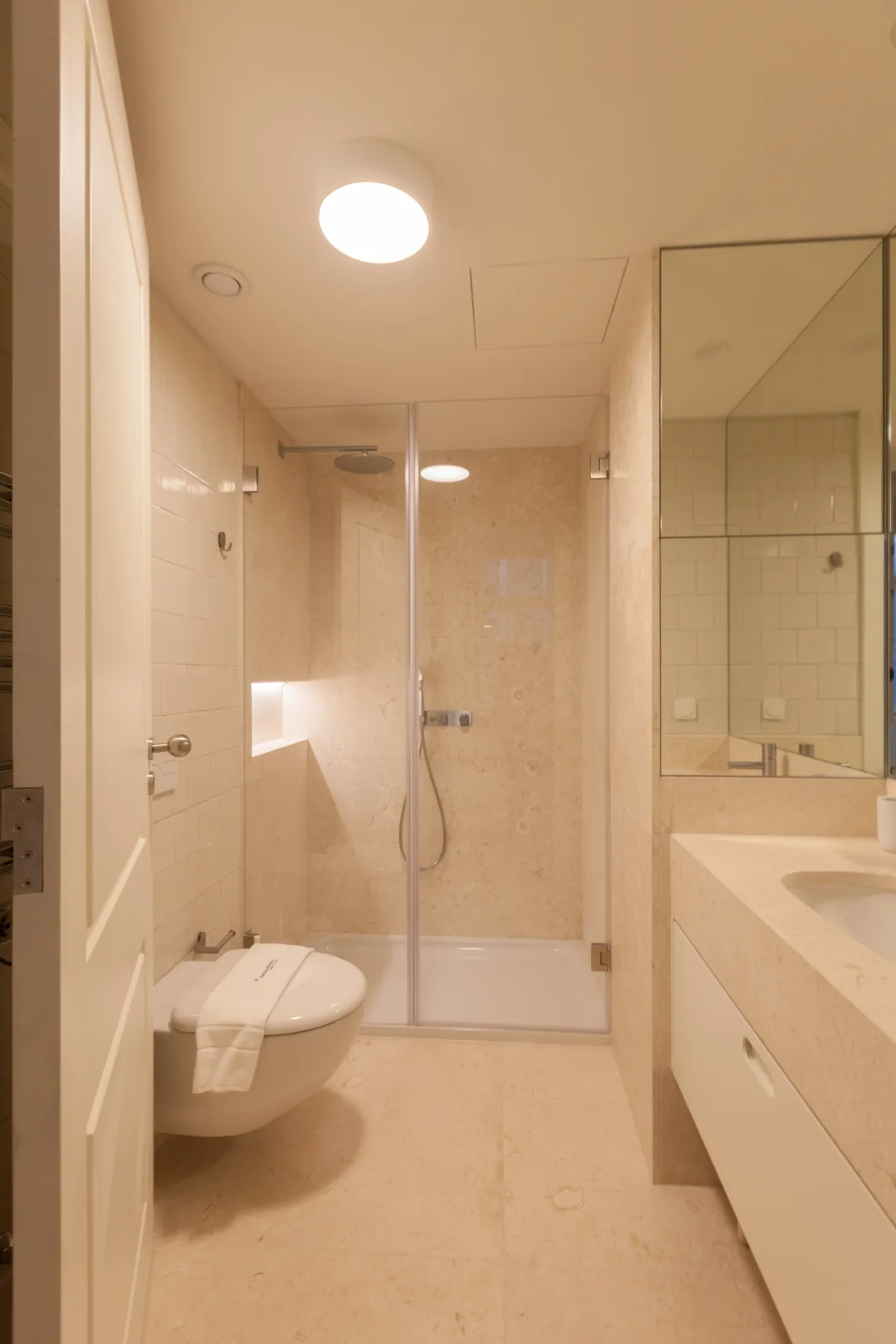 Un baño luminoso con ducha de cristal, inodoro y lavabo.