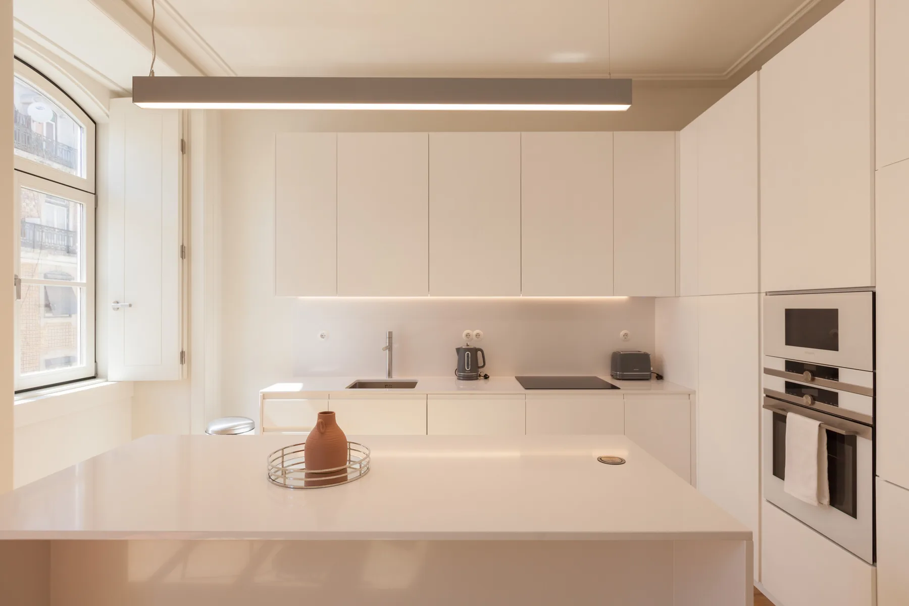 Una cocina moderna y luminosa con armarios blancos y una gran isla central.