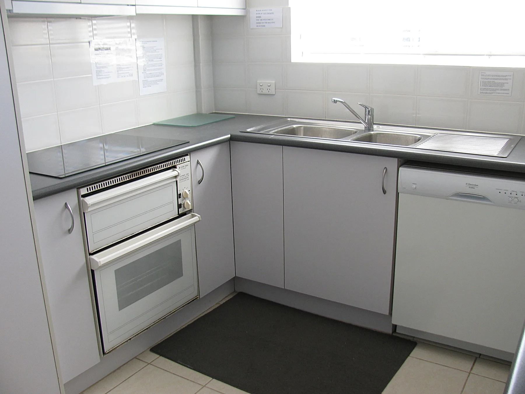 Una cocina compacta tiene un fregadero, una placa de cocina y un horno empotrado.