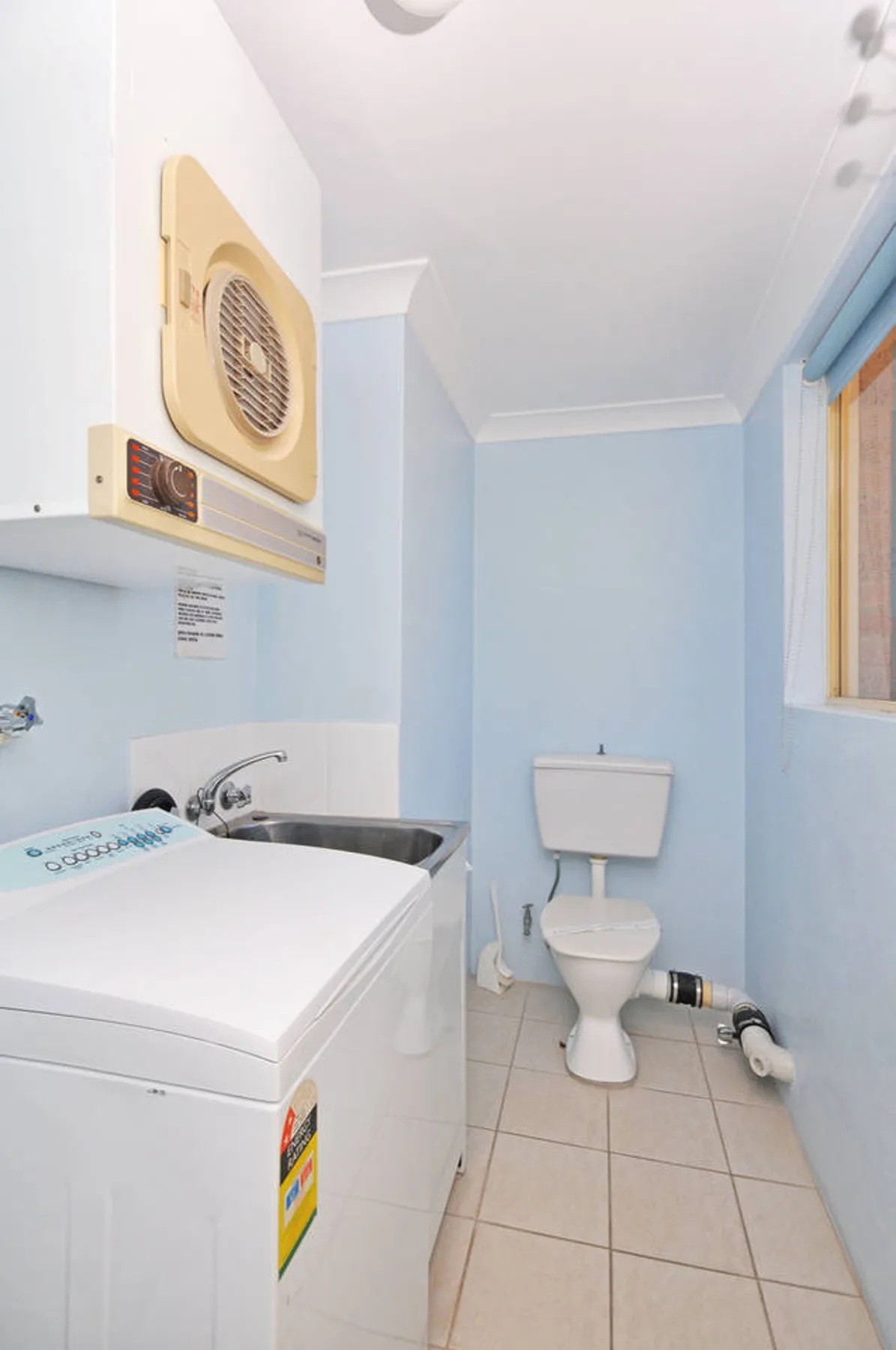 Un baño compacto con inodoro, lavabo y lavadora.