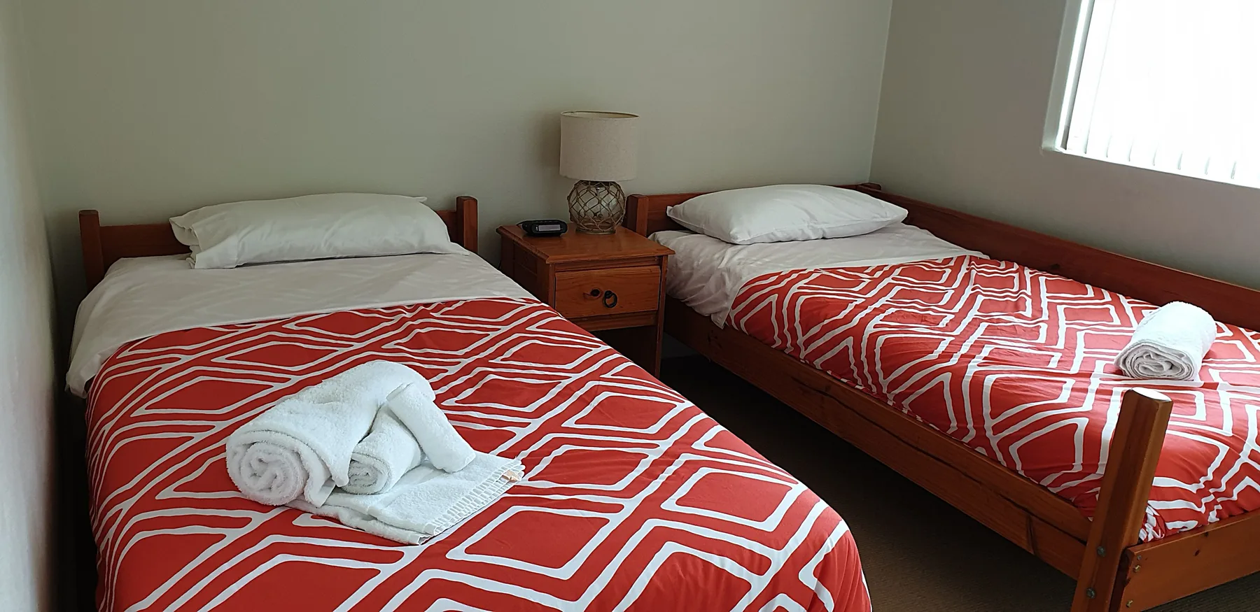 Un dormitorio con dos camas individuales vestidas con ropa de cama roja estampada.
