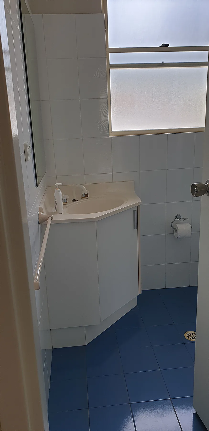 Un baño alicatado con un mueble de lavabo y una ventana esmerilada.