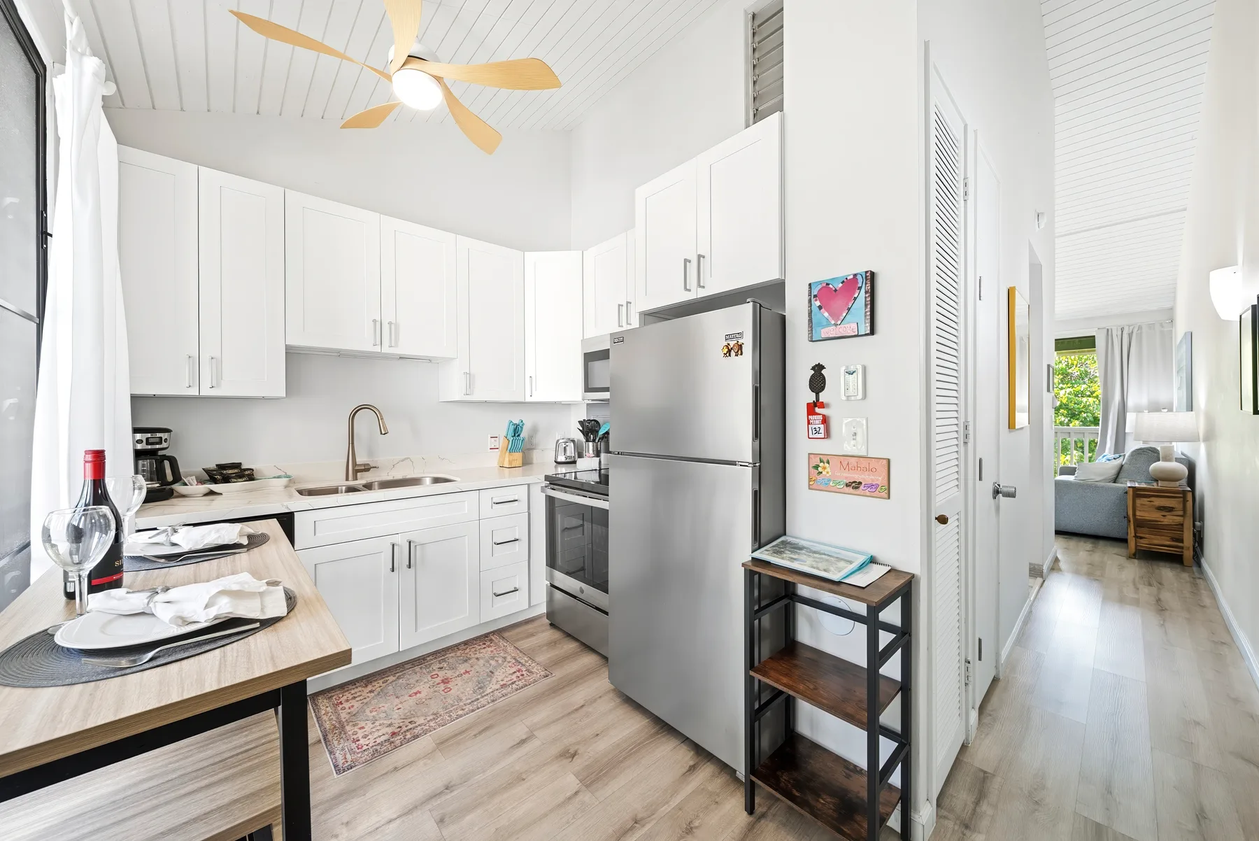 Una cocina luminosa con armarios blancos y un refrigerador de acero inoxidable.