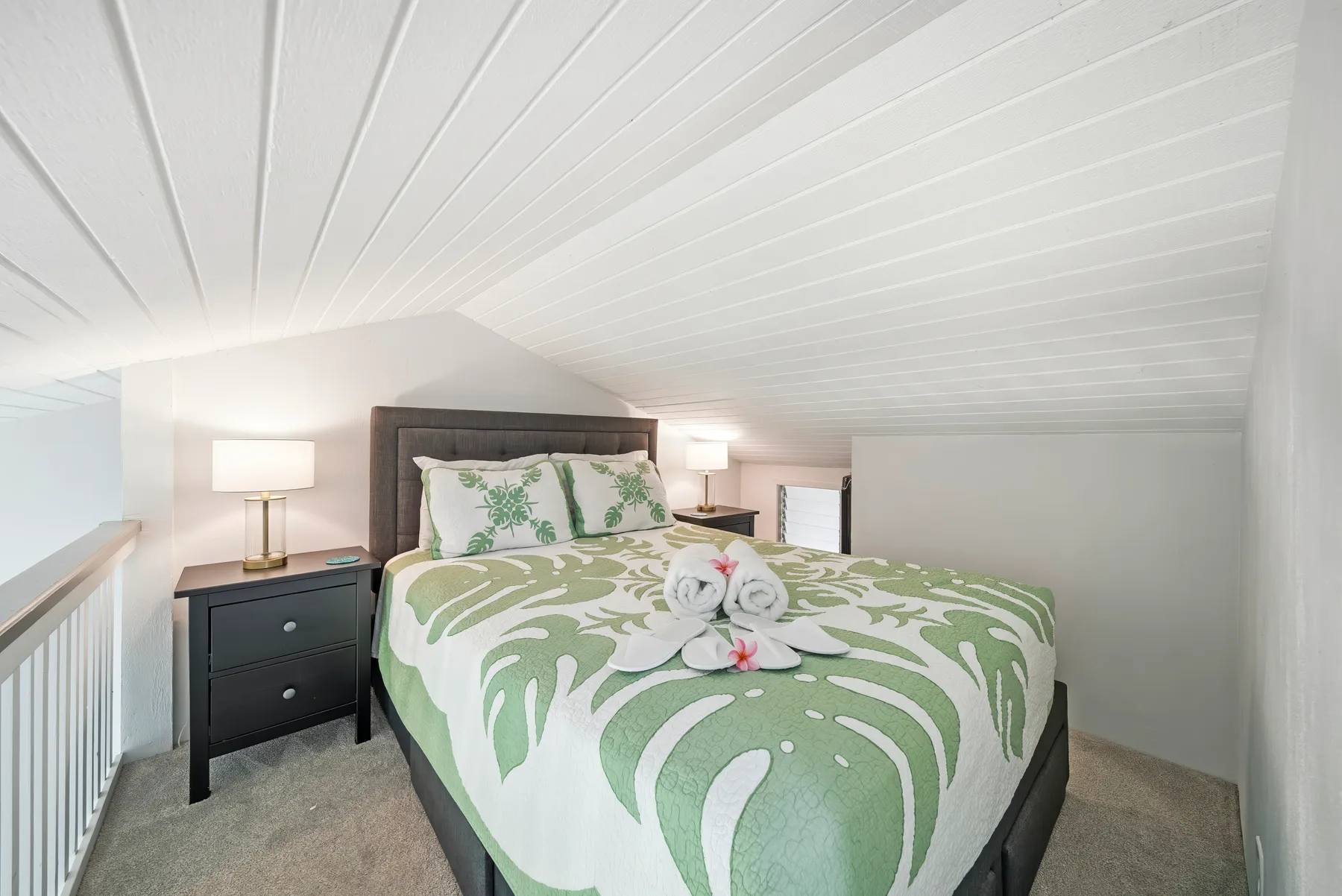 Un dormitorio con una cama cubierta con ropa de cama estampada en verde y blanco.