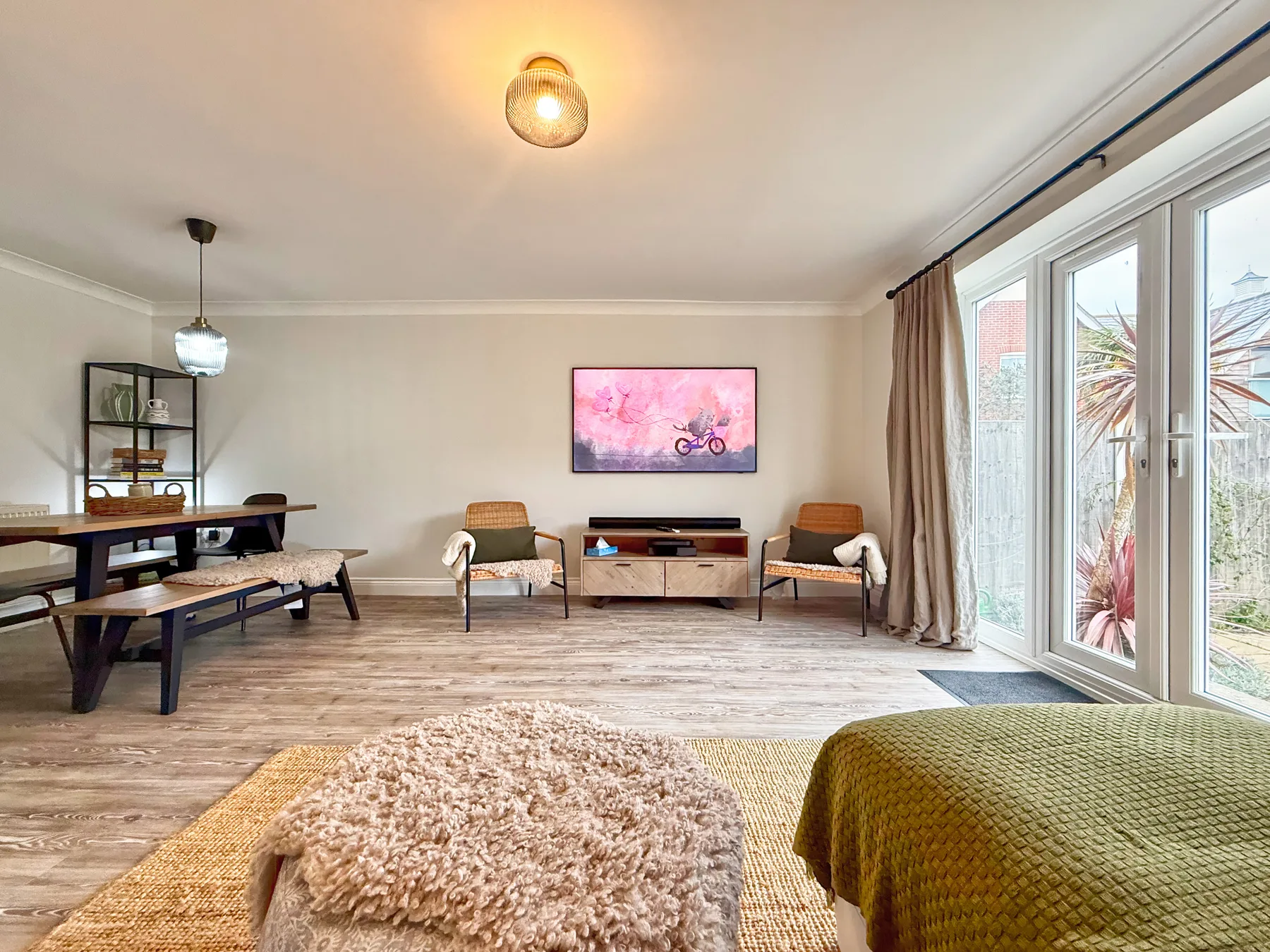 Una sala luminosa con asientos, un televisor y grandes puertas de vidrio.